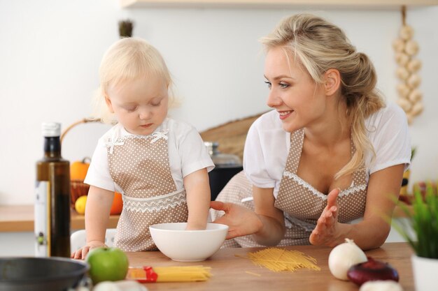 Feliz madre e hija cocinando en la cocina. Pasar tiempo todos juntos, concepto de diversión familiar.