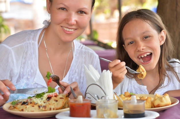 Feliz madre e hija comiendo juntos en la cafetería