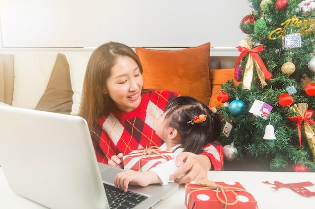 Feliz madre e hija decorando árboles de Navidad y regalos en casa