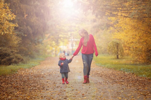 Feliz madre e hija están caminando en un parque de otoño