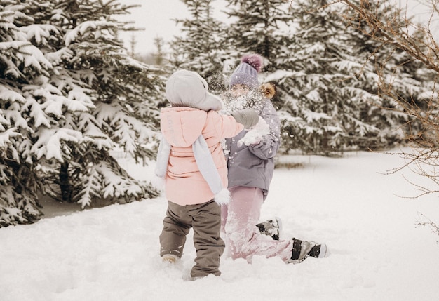 Feliz madre e hija juegan bolas de nieve en un parque natural cubierto de nieve en una nevada. Gran momento divertido. Pasar tiempo juntos en un hermoso día frío de invierno.