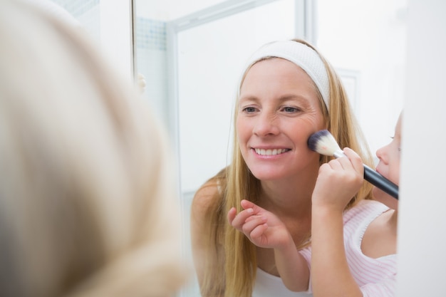 Feliz madre e hija jugando con maquillaje