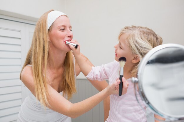 Feliz madre e hija jugando con maquillaje