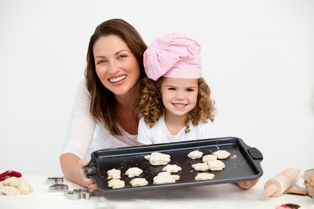 Feliz madre e hija mostrando un plato con galletas