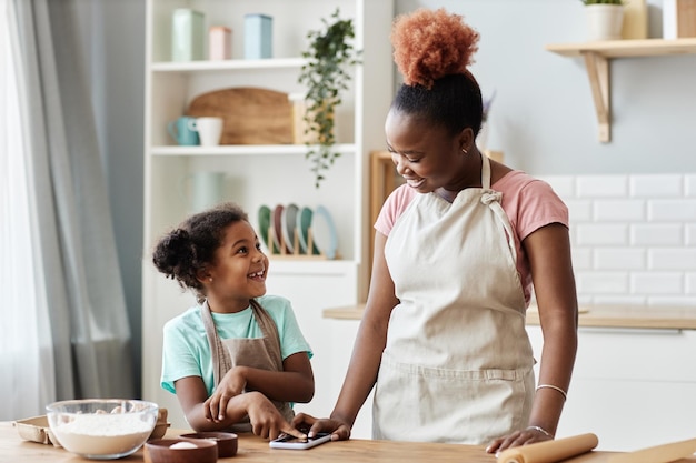 Feliz madre e hija negras cocinando juntas en una cocina acogedora