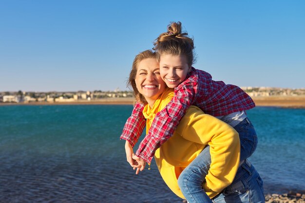 Feliz madre e hija en la orilla del mar relajándose en la playa de arena otoño invierno primavera temporada