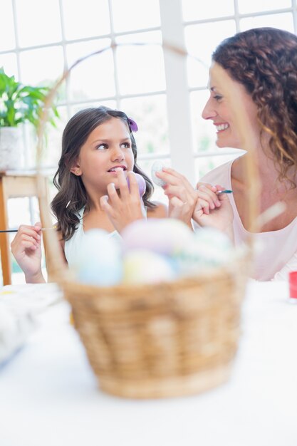 Feliz madre e hija pintando huevos de Pascua