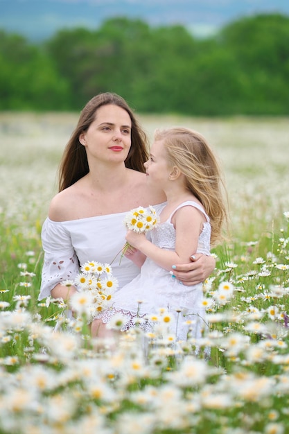 Feliz madre e hija en pradera de manzanilla