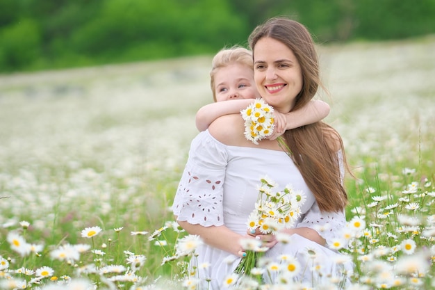 Feliz madre e hija en pradera de manzanilla