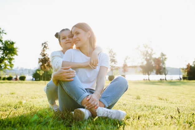 Feliz madre e hija relajándose en el parque. Escena de belleza natural con estilo de vida familiar al aire libre en primavera o verano. Familia elegante feliz descansando juntos, divirtiéndose al aire libre.