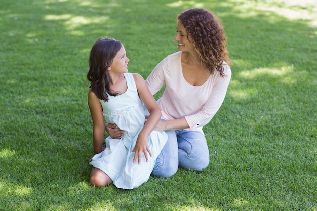 Feliz madre e hija sentada en la hierba