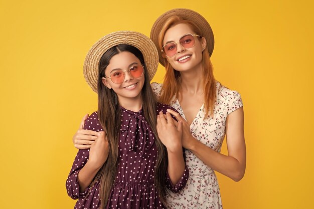 Foto feliz madre e hija en sombrero de paja sobre fondo amarillo