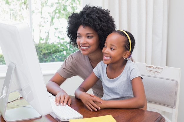 Feliz madre e hija usando la computadora