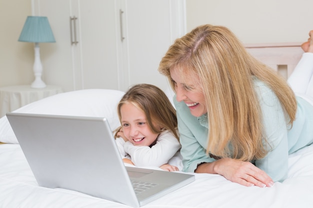 Feliz madre e hija usando laptop