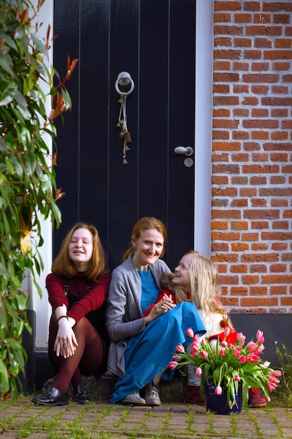 Feliz madre e hijas sentadas en el porche de su casa