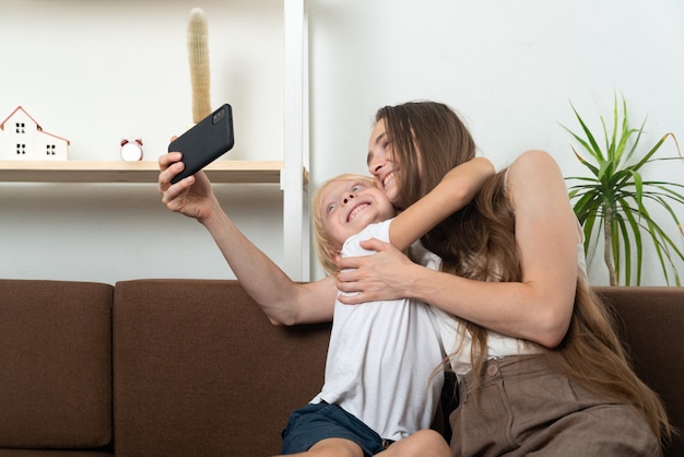 Feliz madre e hijo abrazándose y tomando selfie