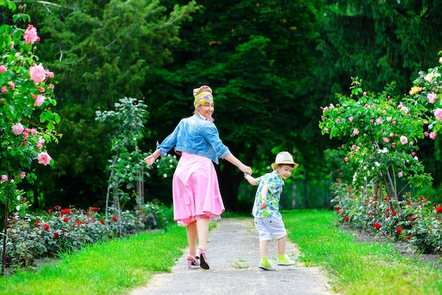 Feliz madre e hijo caminando en el parque de verano con flores.