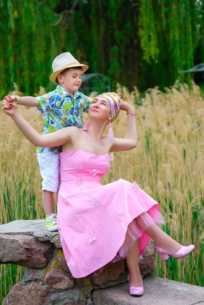 Feliz madre e hijo caminando en el parque de verano con flores.