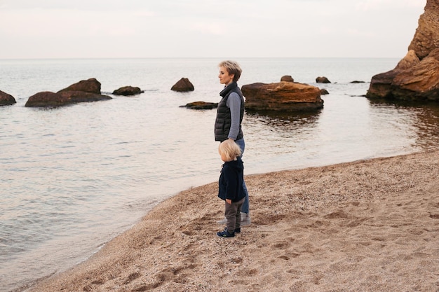 Feliz madre e hijo cerca del mar frío en otoño