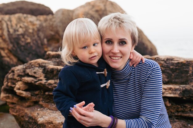 Feliz madre e hijo cerca del mar a orillas del mar en otoño