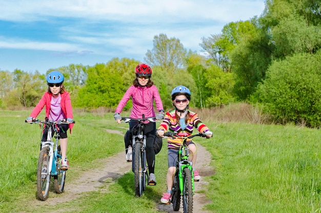 Feliz madre e hijos en bicicleta al aire libre en el parque deporte familiar activo y fitness juntos