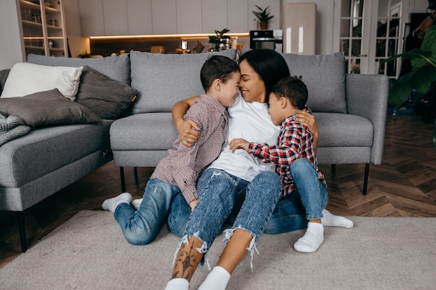 Feliz madre de familia afroamericana y dos hijos jugando y divirtiéndose juntos en casa