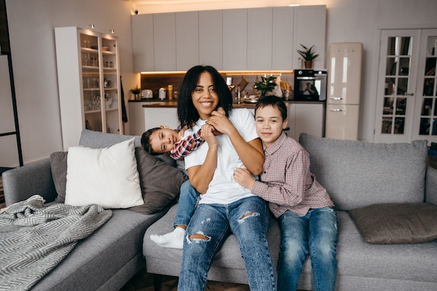 Feliz madre de familia afroamericana y dos hijos jugando y divirtiéndose juntos en casa