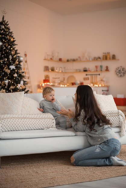 Feliz madre de familia e hija del niño cerca del árbol de Navidad en casa