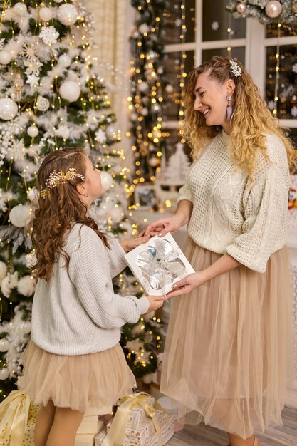 Feliz madre de familia e hija del niño en la noche de Navidad