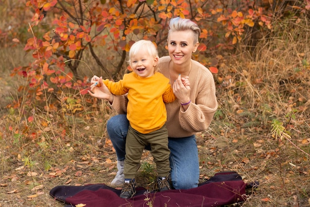 Feliz madre de familia e hijo jugando y riendo en la caminata de otoño