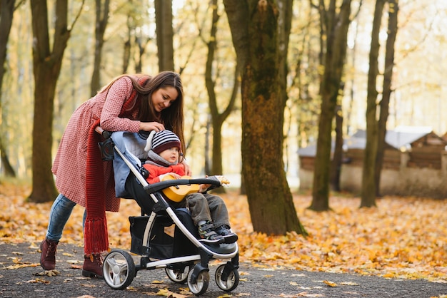 Feliz madre de familia e hijos en otoño caminan en el parque