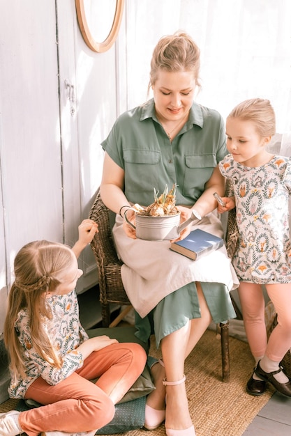 Feliz madre de familia con niños pequeños, hijas, niñas que se divierten juntas en el campo de los suburbios, en un día soleado de verano, madre sincera e hijos, momento acogedor de la vida rústica doméstica, la gente ama y cuida