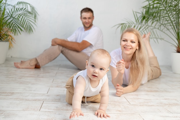 Feliz madre de familia, padre y bebé en casa divirtiéndose, bebé gateando en primer plano