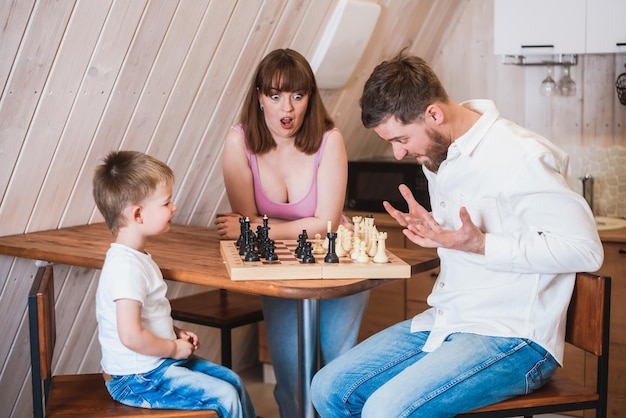 Feliz madre de familia papá y su hijo jugando al ajedrez en la habitación