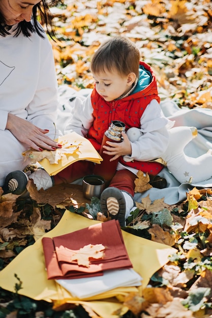 Feliz madre de familia y pequeña hija pequeña divirtiéndose juntos en un picnic de otoño
