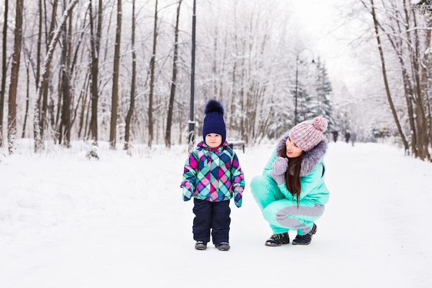 Feliz madre de familia y su hija bebé en un paseo de invierno en el bosque