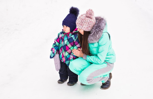 Feliz madre de familia y su hija bebé en un paseo de invierno en el bosque