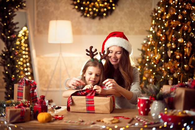 Una feliz madre de familia y su hijo empacan regalos de Navidad
