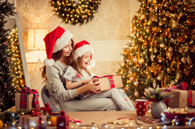 Una feliz madre de familia y su hijo empacan regalos de Navidad