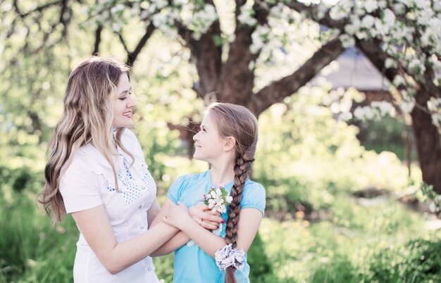 Feliz madre con hija en el jardín de primavera