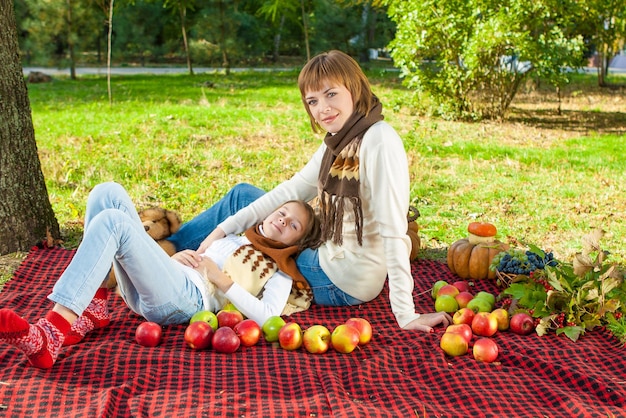 Feliz madre con hijita en el parque de otoño