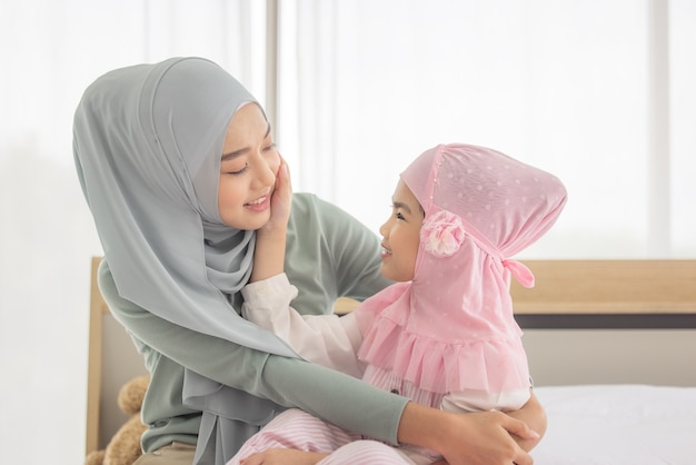 Feliz madre musulmana caricias con su hija en la cama