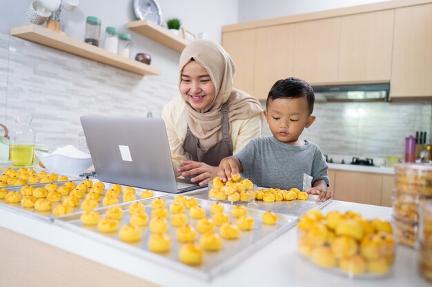 Feliz madre musulmana trabajando desde casa haciendo orden de comida de pastel de piña nastar