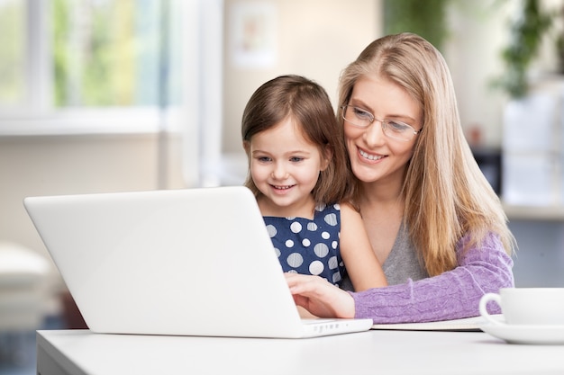 Feliz madre ocupada trabajando con un niño en la computadora portátil