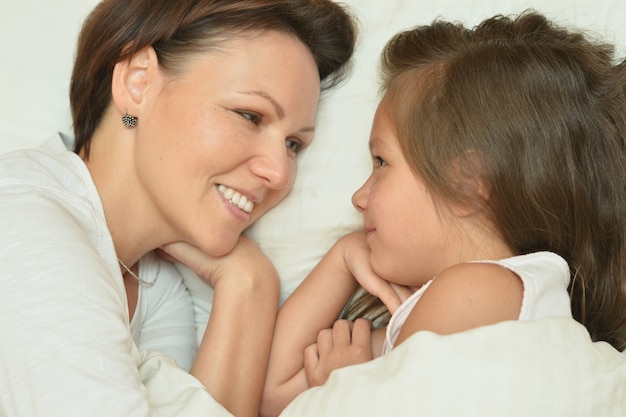 Foto feliz madre pasar tiempo con la pequeña hija en la cama