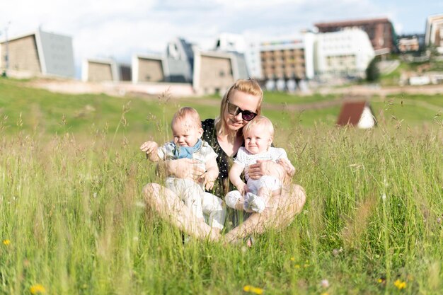 Feliz madre soltera con gemelos en el parque natural