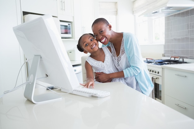 Feliz madre sonriente con su hija usando la computadora