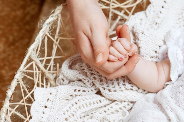 Feliz madre sosteniendo la mano de sus hijos recién nacidos