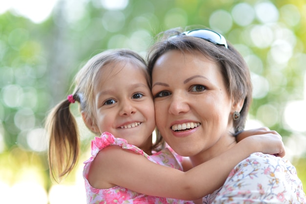 Feliz madre con su hija caminar en el parque de verano