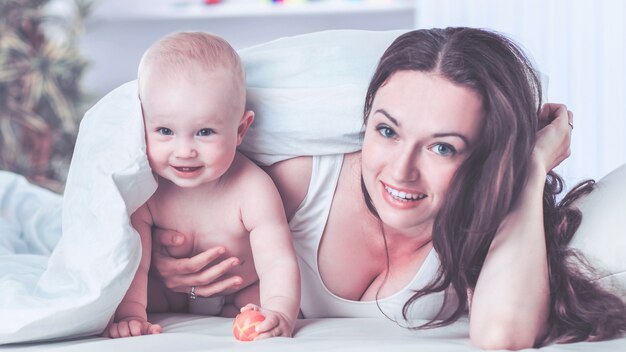 feliz madre y su hijo jugando en el sofá del dormitorio